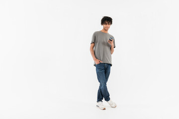 Full body of young smiling male student black man guy boy in casual clothes standing holding using...