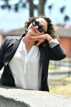 Retrato de una Chica Guatemalteca joven y bella, sonrisa hermosa usando lentes de sol y cabello rizado. Toma Vertical.