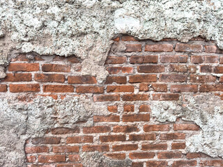 Exposed red brick wall texture with cracked cement plaster