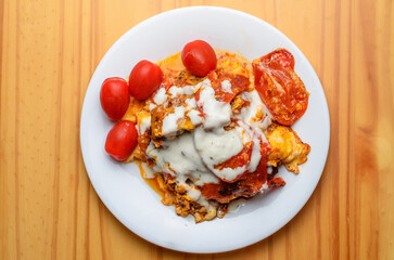 Fried eggs with tomatoes and mayonnaise on white plate as unhealthy food