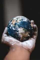 A person holds a chalk-dusted globe, symbolizing artistic environmental awareness and responsibility