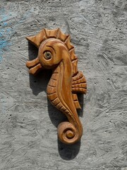  Seahorse-shaped wooden carving mounted on textured surface