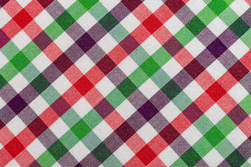 The texture of linen fabric in a large cage of green, red and white. Scottish tailoring material. Checkered fabric