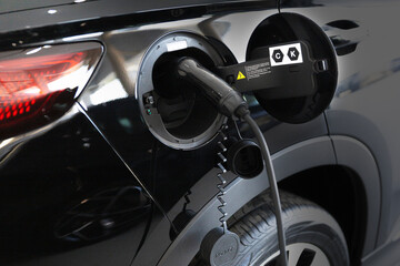 EV plug connected black EV Car for recharging battery energy.