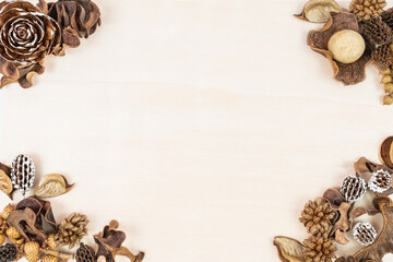 Rustic made of natural materials decor, fir cones and flowers over light wooden table background.