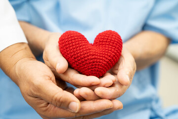 Asian elder senior woman patient holding red heart in hospital.