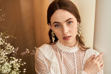 Elegant young woman in vintage dress amid delicate flowers in soft light