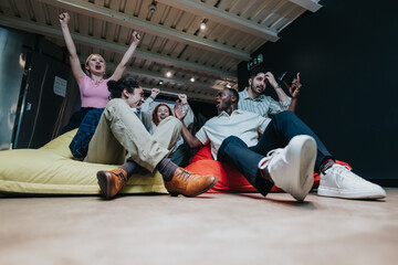 A diverse team of coworkers enthusiastically enjoying a moment of celebration while seated on...