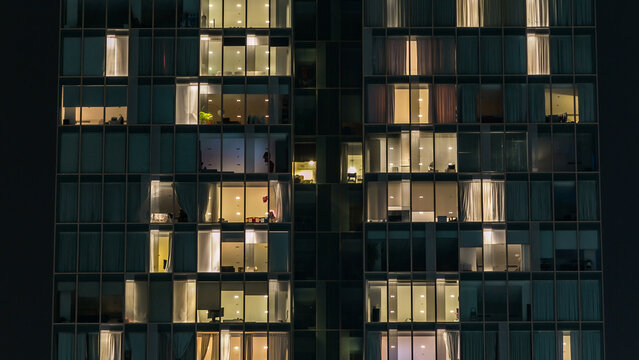 window of the multi-storey building of glass and steel lighting and people within timelapse