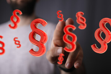 Abstract image of red paragraph symbols hovering near a person's hand, representing legal concepts...