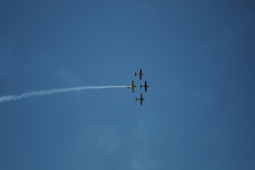 Aerobatic Formation of Four Propeller Planes Against a Clear Blue Sky