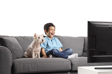 Child and dog sitting on a sofa and watching tv