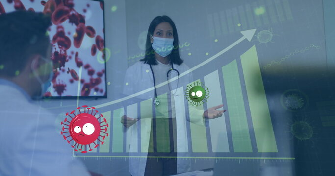 Image of red and green virus cells over female doctor in face mask and graphs - Powered by Adobe