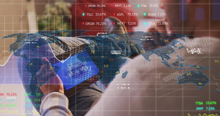 Reclining male wearing headphones reading tablet on sofa in office lounge, with stock data overlay