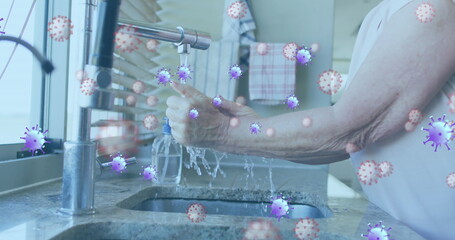 Image of purple virus cells over hands pf caucasian senior man washing hands