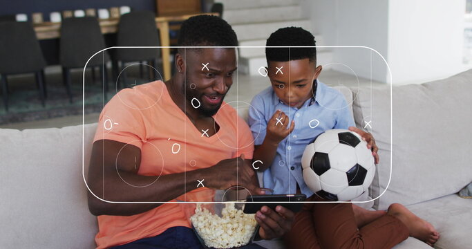 Fototapeta Image of soccer field over african american father and son watching match in smartphone