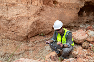 Obraz premium A geologist is examining the mineral content of soil and recording it on paper