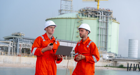 Workers in safety gear discuss project details at a natural gas facility near the coast during...
