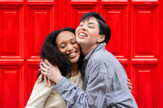 Friends embracing with joy against a bright background