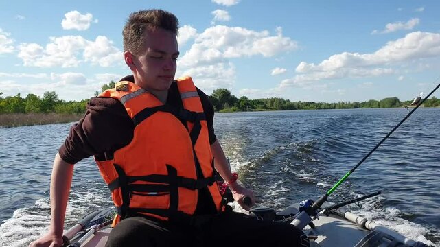 teen boy drives a motor PVC boat, fishing on trolling