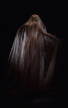 Beautiful blonde woman posing in brown veil by candlelight on dark background, gothic queen, art style..