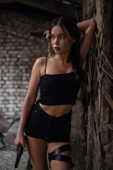 Naklejka premium Beautiful woman super agent with pistols in hands posing on abandoned building background..