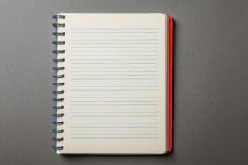 An open spiral notebook with lined pages lies on a gray surface, ready for writing or note-taking.
