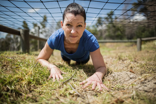 Fototapeta Low net barrier stretching over grass-and-dirt ground on training course under clear sky