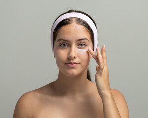 Eye cream skin care beauty routine: young woman in product application for under-eye treatment.
