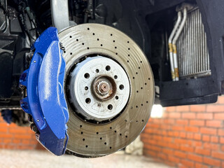 Car ventilated front brake disc with blue caliper. Modern perforated brake disc with ventilation...