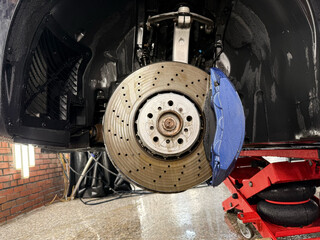 Car ventilated front brake disc with blue caliper. Modern perforated brake disc with ventilation...