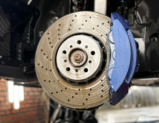 Car ventilated front brake disc with blue caliper. Modern perforated brake disc with ventilation...