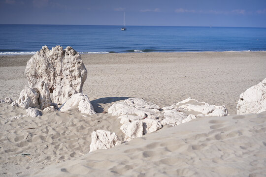 Tranquil beach with rocky shoreline and sailboat on serene horizon. Patara Beach in Turkey