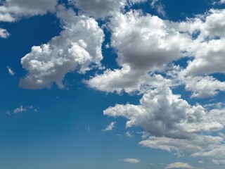 Obraz premium Blue sky with clouds background, sunny day. White and grey fluffy cloudscape
