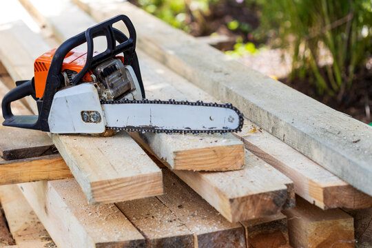 An old chainsaw that sawed through a lot of boards is located on freshly sawn wood