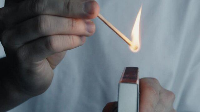 Macro shot of a match being lit through friction with the striking surface 