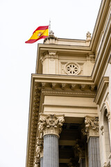 Spanish flag waves atop an impressive building in Madrid, showcasing architecture and national...