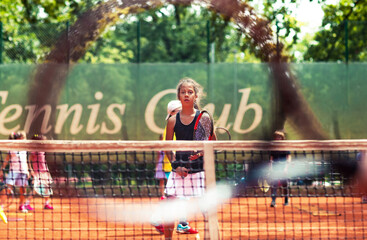 Young girl in tennis court training session learning to play tennis at the club