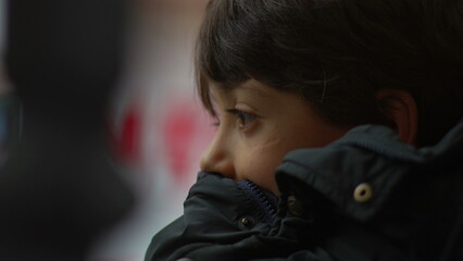 Young boy sitting and reflecting quietly, close-up of thoughtful expression, resting in a calm and...