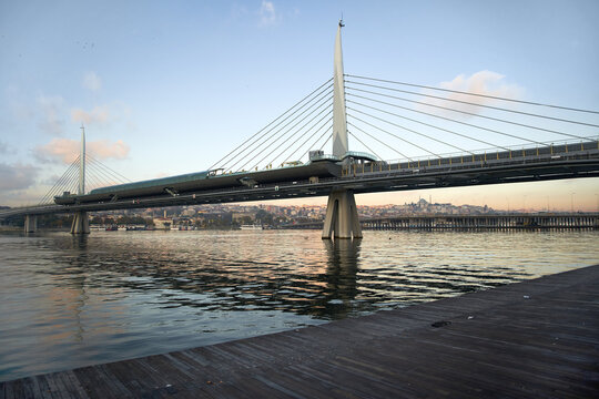 Modern suspension bridge over river at sunset with cityscape background - Powered by Adobe