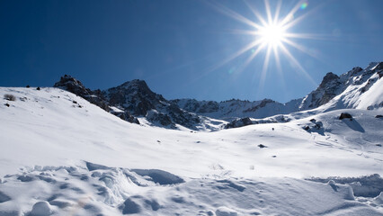 snowy mountains daylight landscape with fresh clear snow, bright sun, blue sky