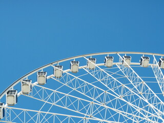 Large white Ferris wheel with closed gondolas against clear sky. Eye-catching geometry, strong...