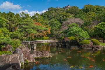 Fototapeta na wymiar Stone bridge over the carp pond in Oyashiki Park of the Koko-en Garden on a sunny autumn day, Himeji, Hyogo Prefecture, Japan