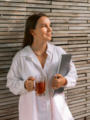 Woman staying with laptop and holding cup of tea