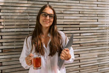 Young woman in glasses staying with laptop and cup of tea