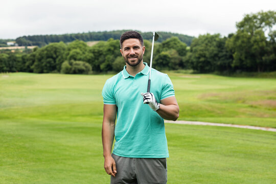Man in his twenties holding golf club on golf fairway wearing polo shirt with golf glove