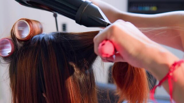 Hairdresser styling woman's hair with blow dryer and brush