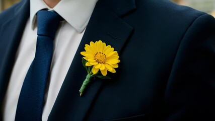Groom in formal suit wearing a bright yellow flower boutonniere during a spring wedding ceremony in a garden setting
