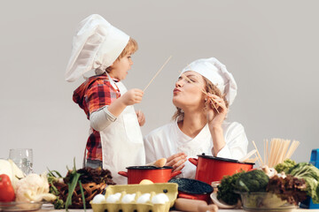 Mother and child cooking together. Kid baby helping mom to cooking in kitchen. Mother and son cooking healthy meal. Child chef with Mother with apron cooking on kitchen. Mom and baby chef.