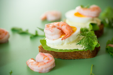 Appetizing breakfast with shrimp, egg and greens on top